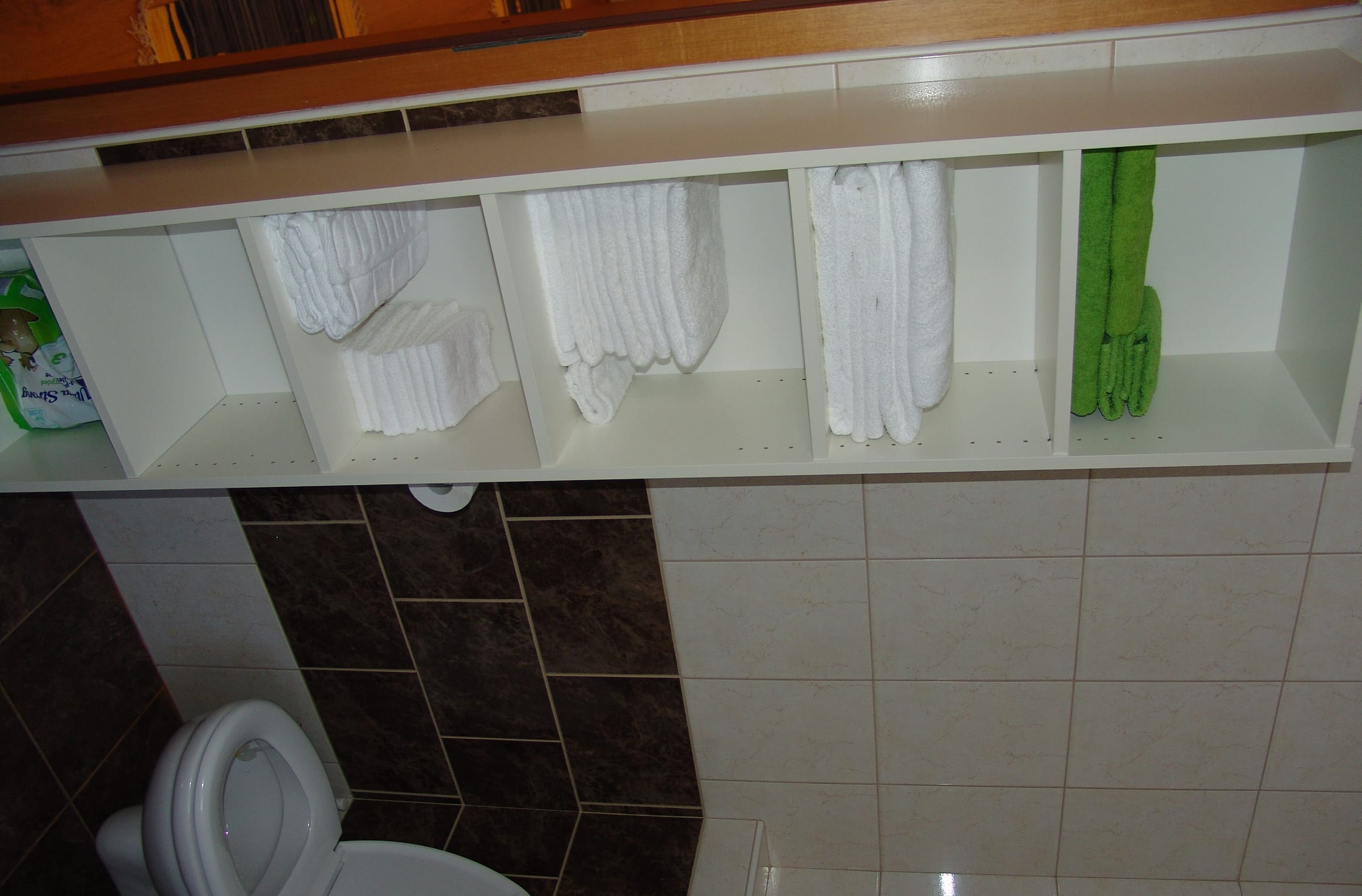A tiled bathroom with a toilet and towels hanging on a rail.