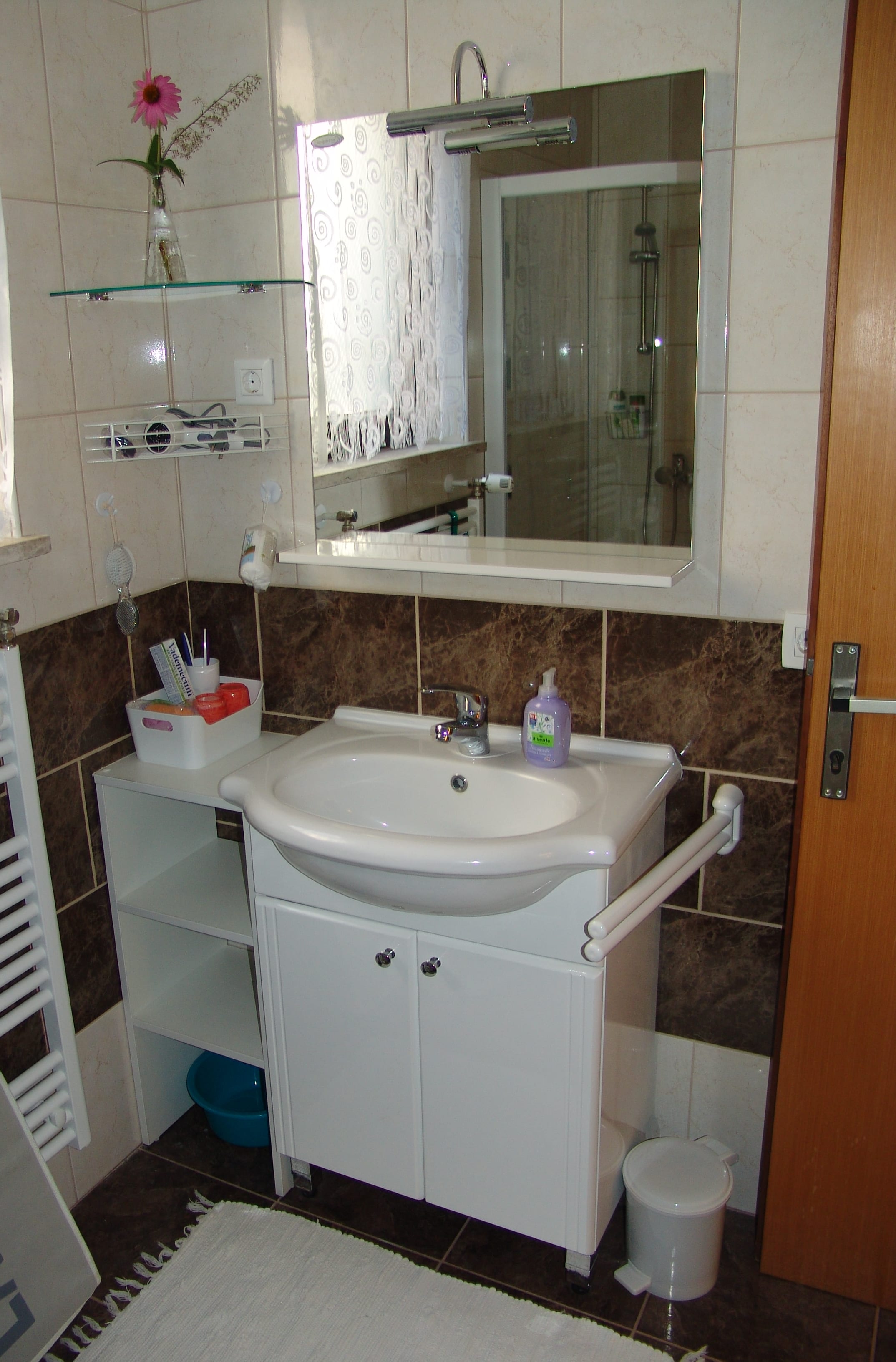 A washbasin on a white cabinet under a mirrored cupboard, with a heated towel rail alongside.