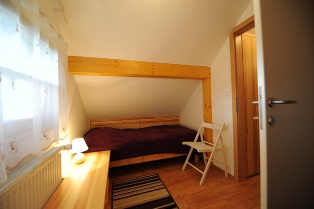 A twin bedroom under the eaves with two single beds, bedside lamps and a wooden floor.
