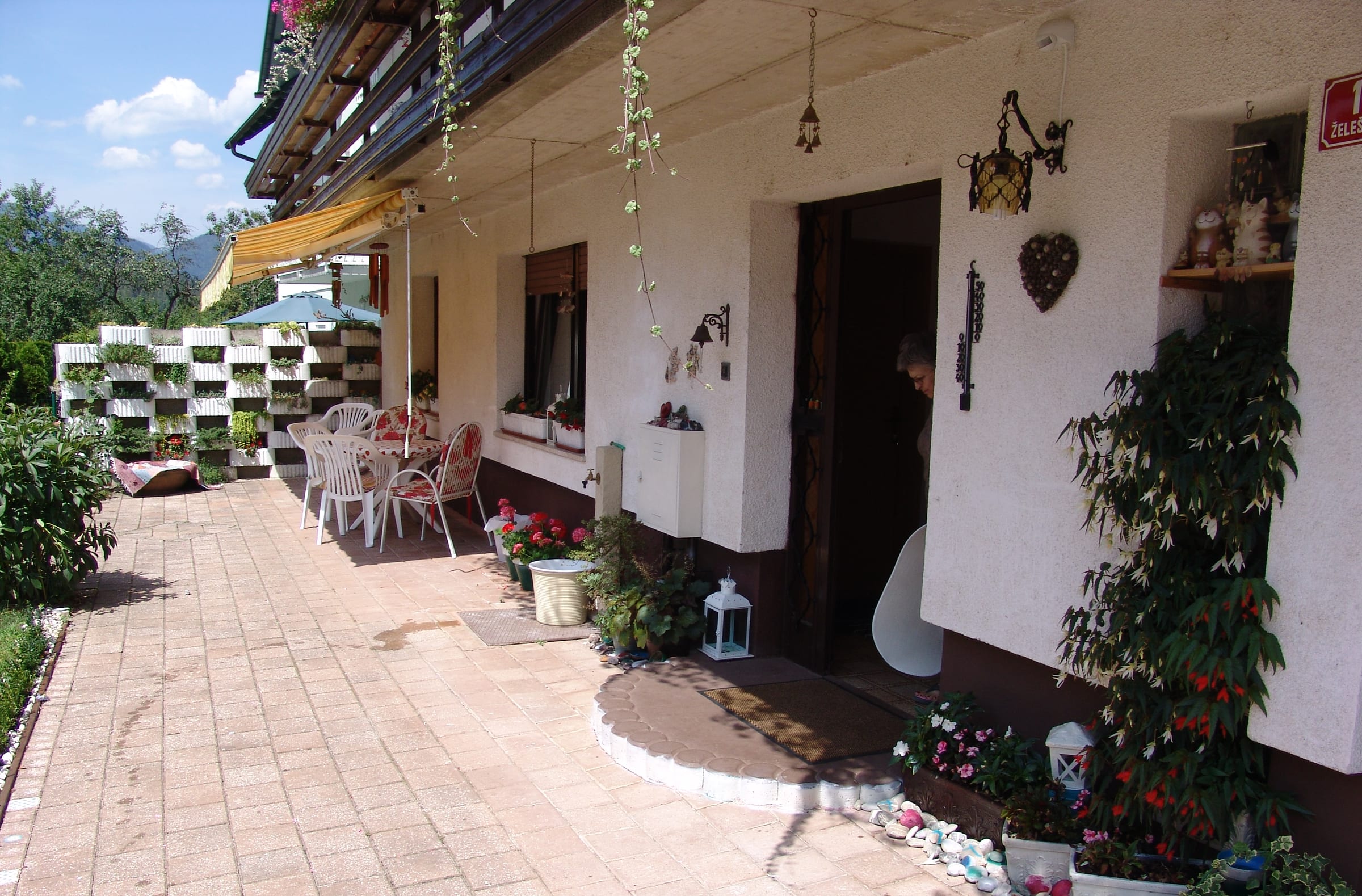 A paved path running alongside the house, past window boxes and a bench, towards the garden.
